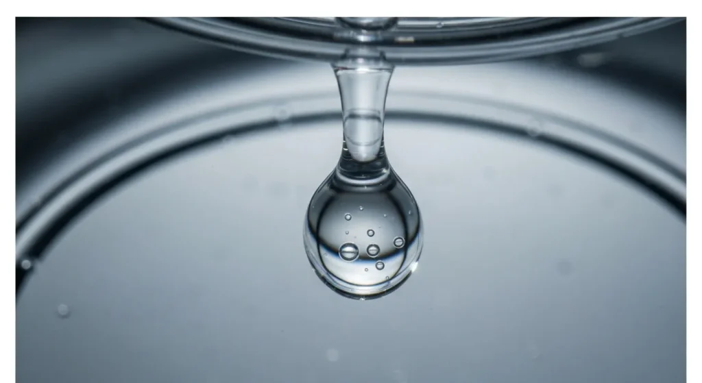 O probă de apă îmbuteliată examinată la microscop, arătând particule mici de plastic.