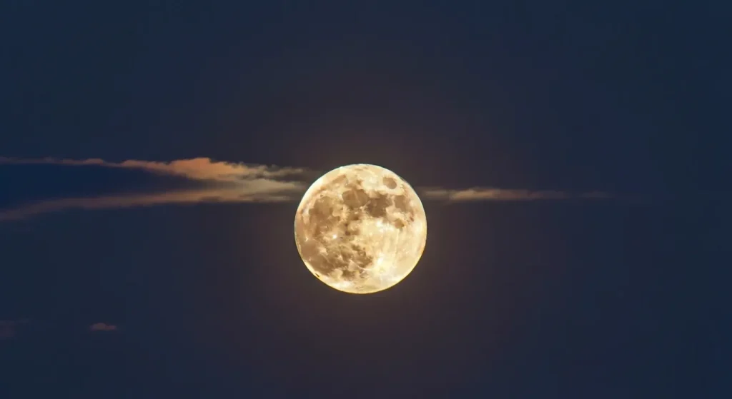 O imagine a unei superluni mari și luminoase, aproape de orizont, cu un cer întunecat.