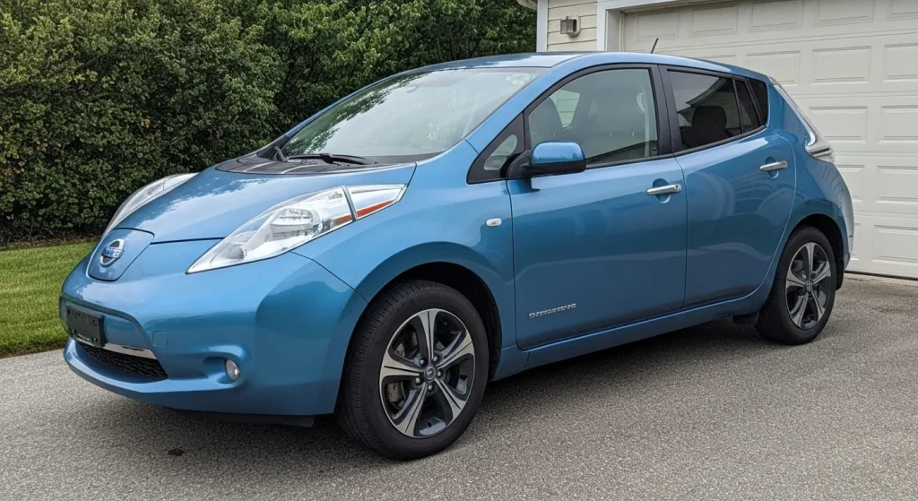 Un Nissan Leaf albastru, parcate în fața unei case.